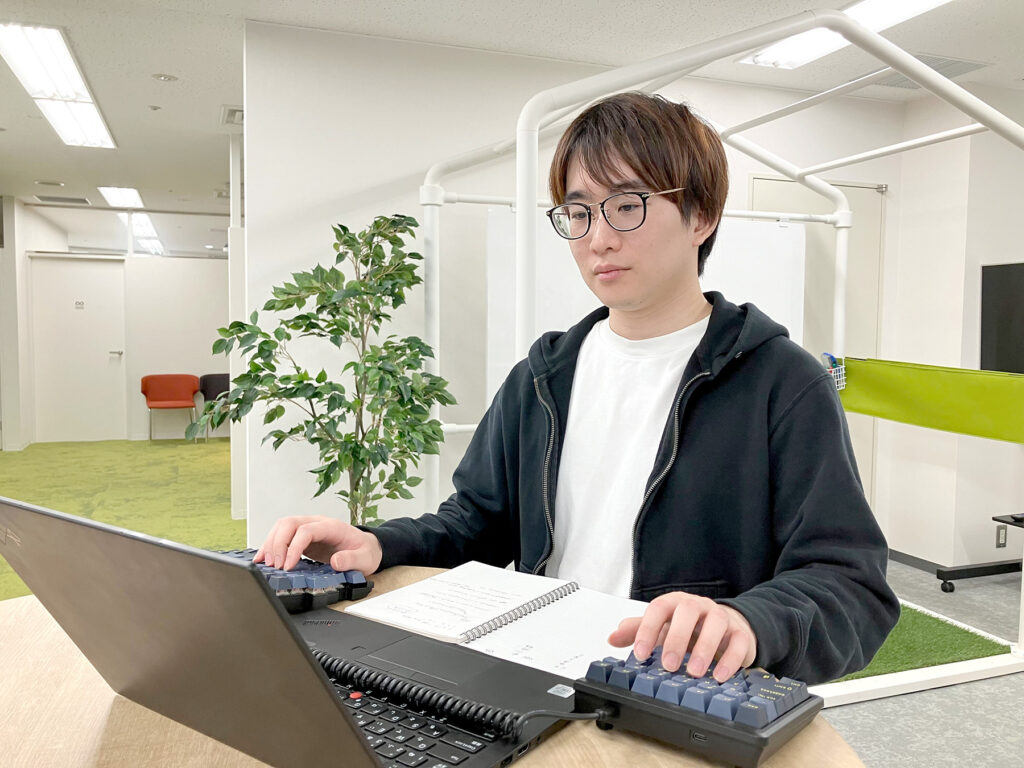 写真:左右分離型キーボードを使い、ノートPCで仕事をするY.C.さん